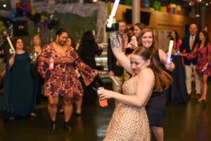 Grown-up night at the museum event. People dancing with glow sticks, enjoying a party atmosphere. Museum event fun.