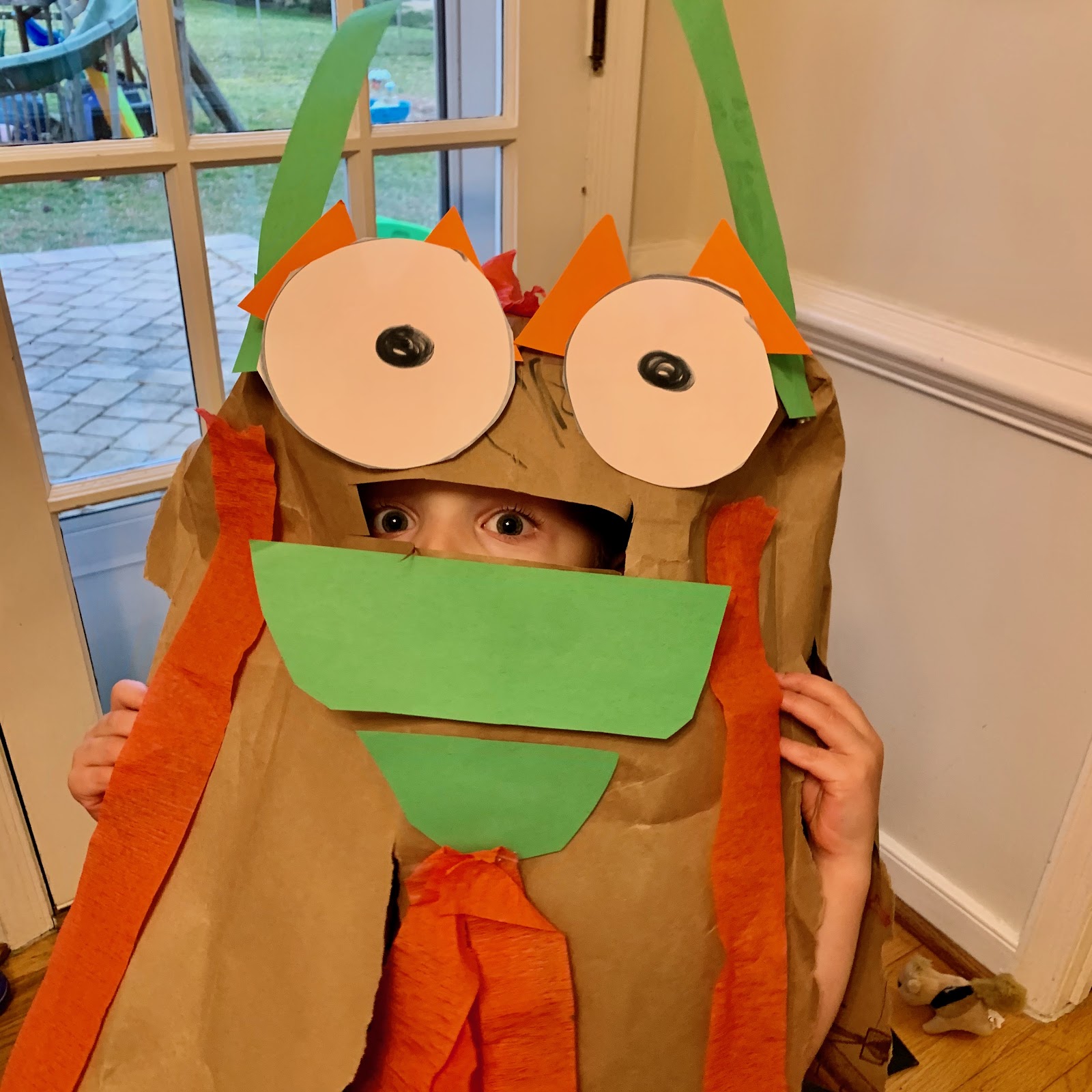 Child in Lunar New Year drum costume. Homemade craft with paper bag, green and orange accents. Festive DIY project.