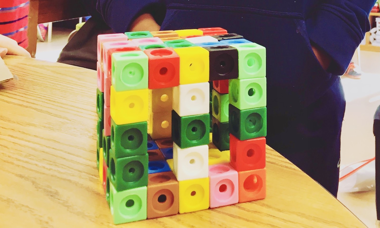 Colorful cube built with blocks. Educational toy for kids. Building blocks on a wooden table.