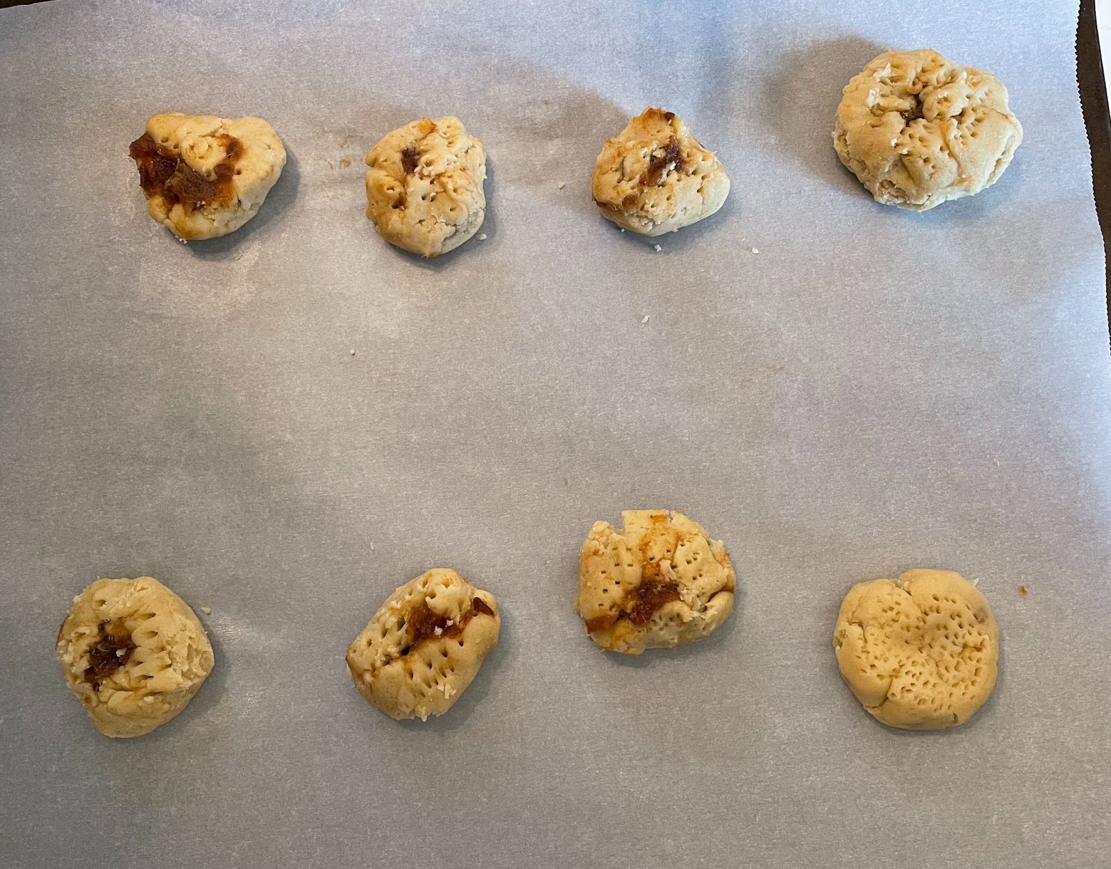 Eid Al-Adha baking: Homemade date-filled cookies on parchment paper, ready for the oven. Celebrate with traditional treats.