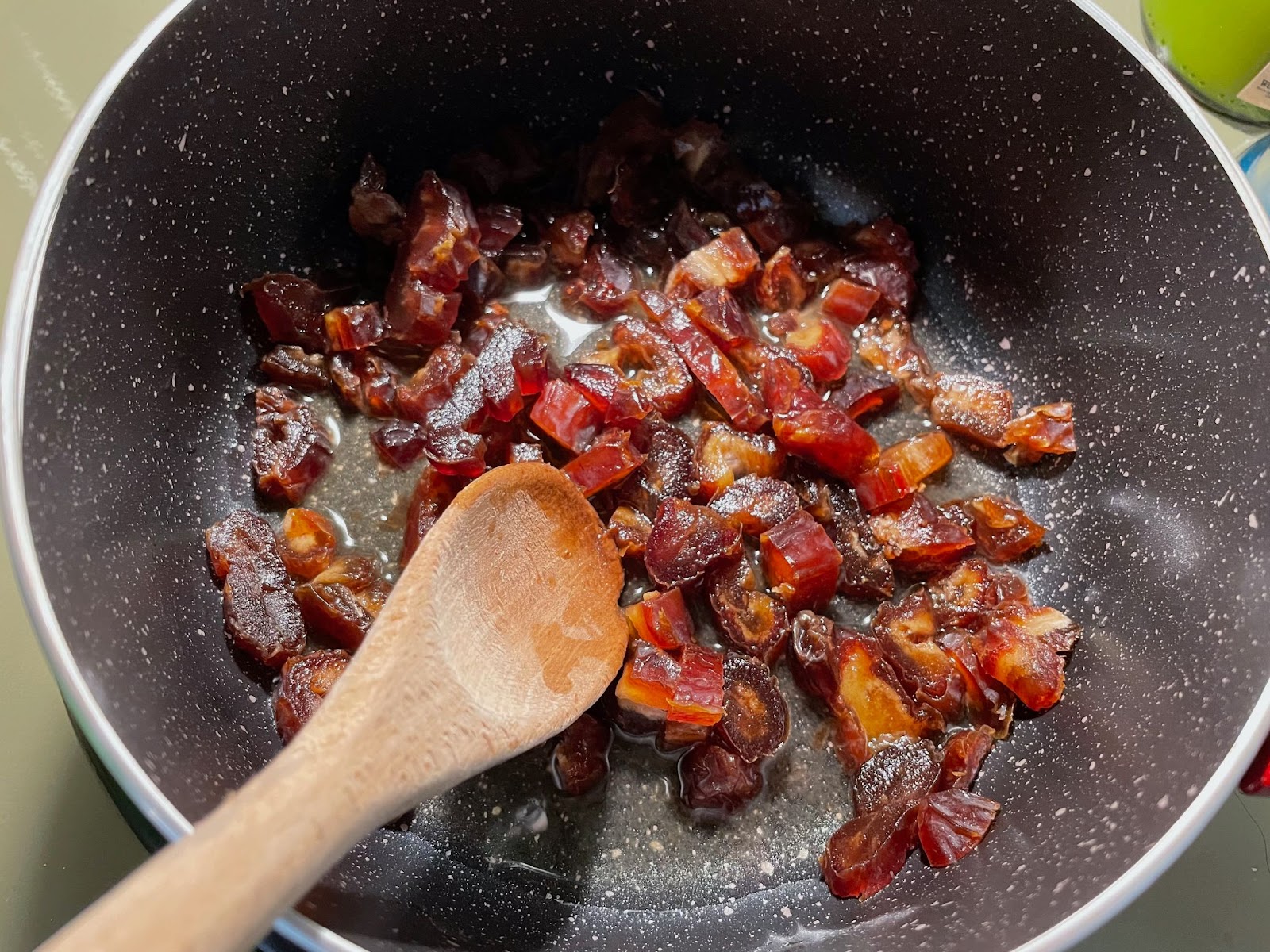 Eid Al-Adha recipe: Dates cooking in a pot with a wooden spoon. Preparing a sweet treat for the Eid celebration.