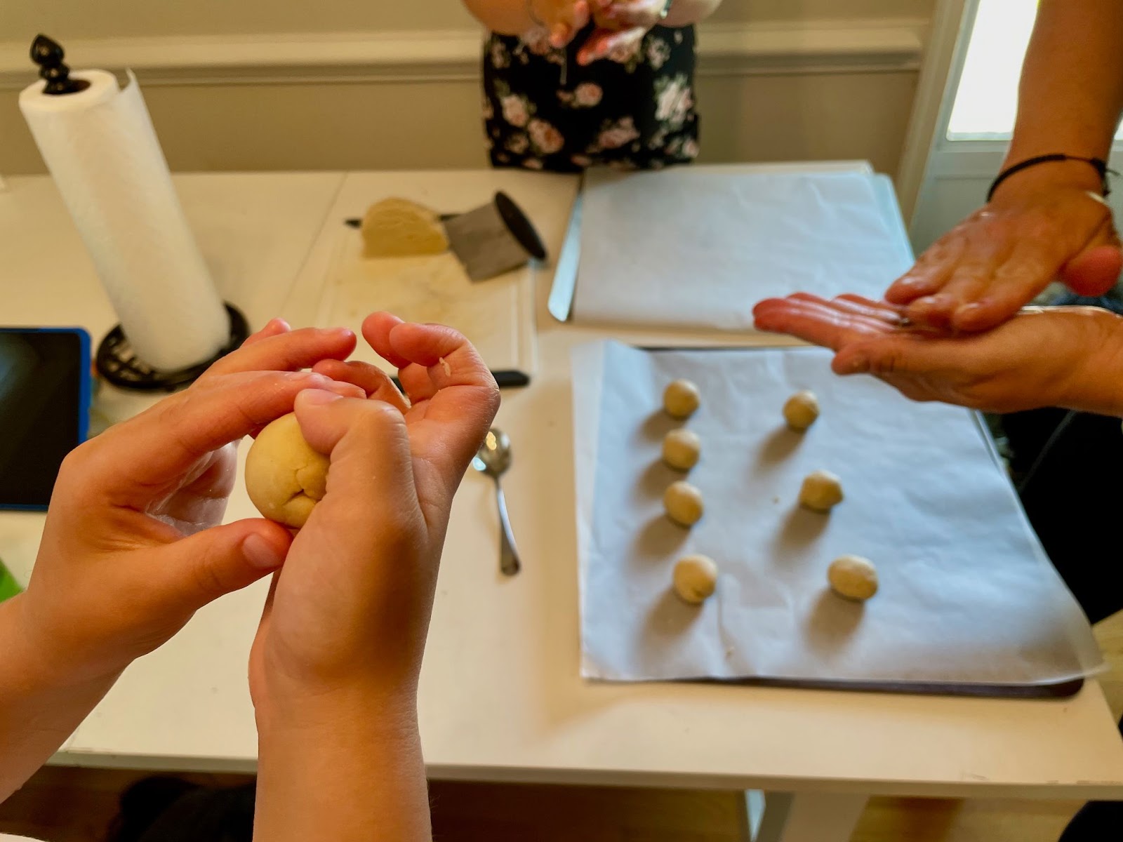 Celebrating Eid Al-Adha with baking. Hands rolling dough balls on a baking sheet. Family cooking together, preparing treats.