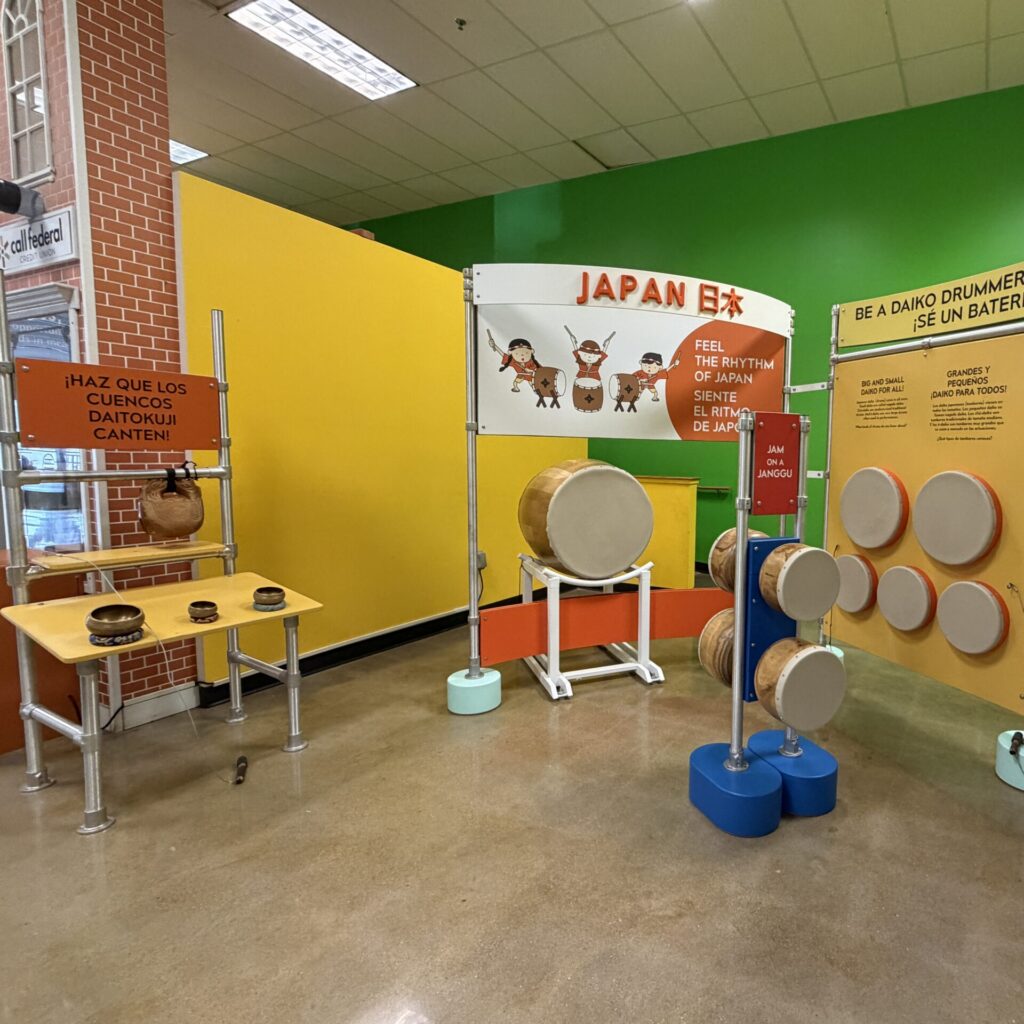 Japanese-themed music station features a large taiko drum, smaller wall-mounted percussion, and bilingual instructions.