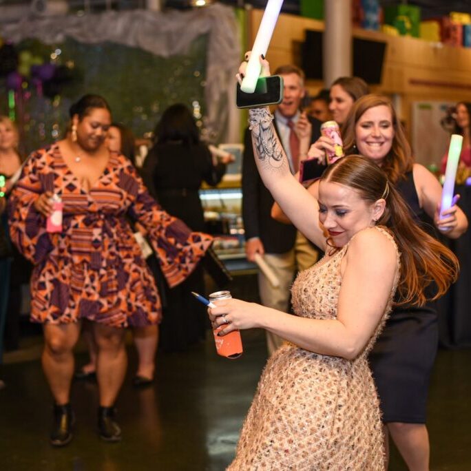 Grown-up night at the museum event. People dancing with glow sticks, enjoying a party atmosphere. Museum event fun.